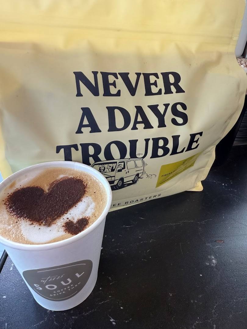 Takeaway coffee cup with heart art and a bag of coffee beans
