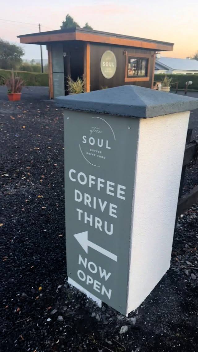 Directional sign and small wooden drive-thru coffee cabin at sunset