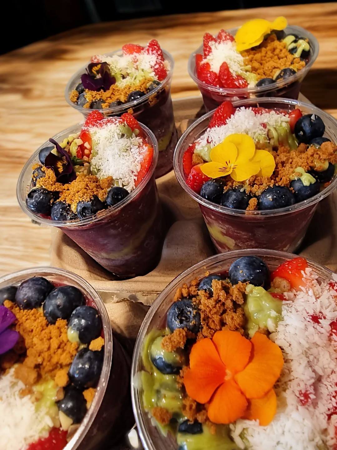 Açaí bowls in clear cups topped with fruit and granola