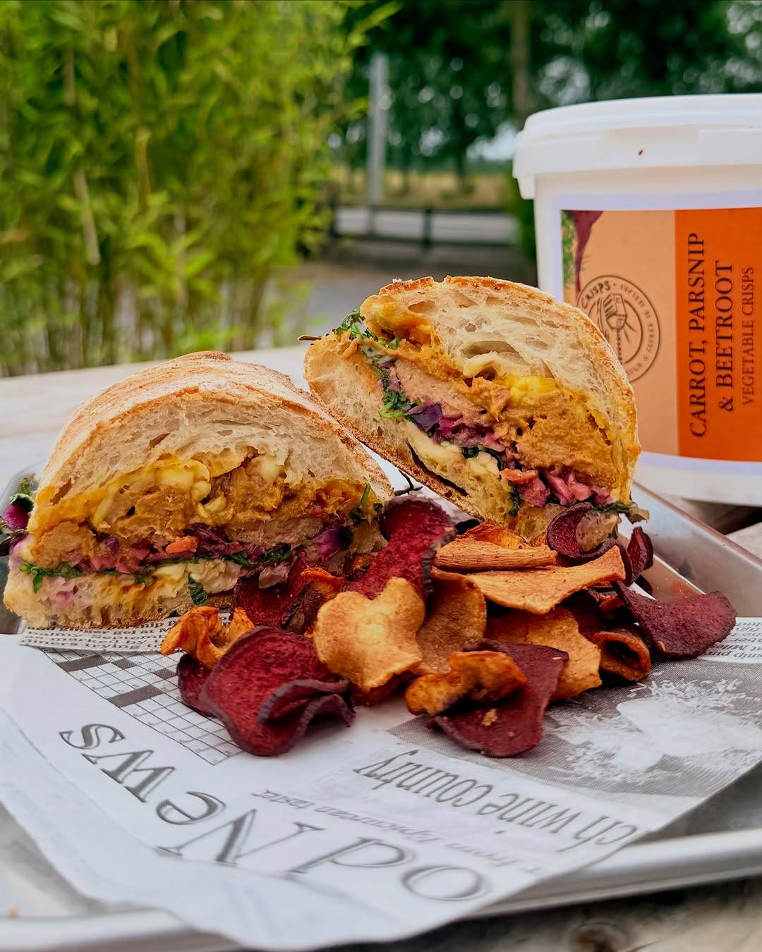 Freshly made sandwich cut in half served with colorful vegetable crisps